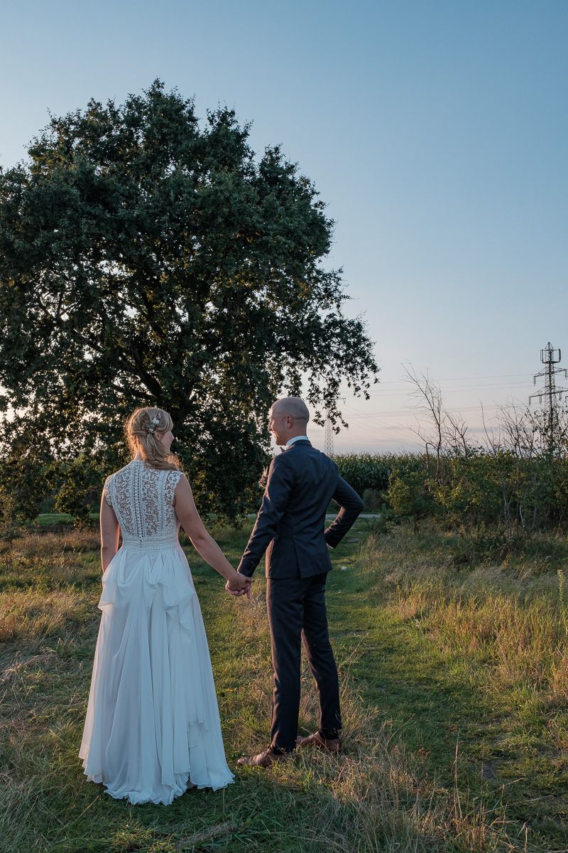 Anna und Jonas stehen Hand in Hand unter einem großen Baum