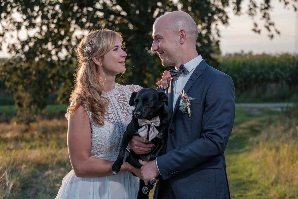 Anna und Jonas mit ihrem Hund auf dem Arm in der Abendsonne