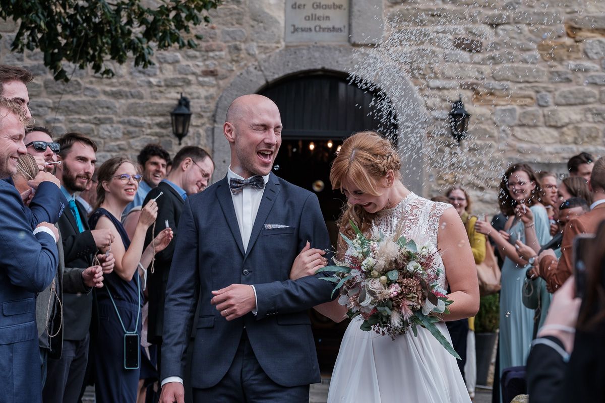 Anna und Jonas verlassen lachend die Kirche, die Gäste jubeln