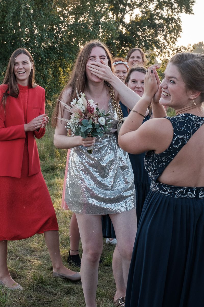 Freundinnen lachen, nachdem eine von ihnen den Brautstrauß gefangen hat