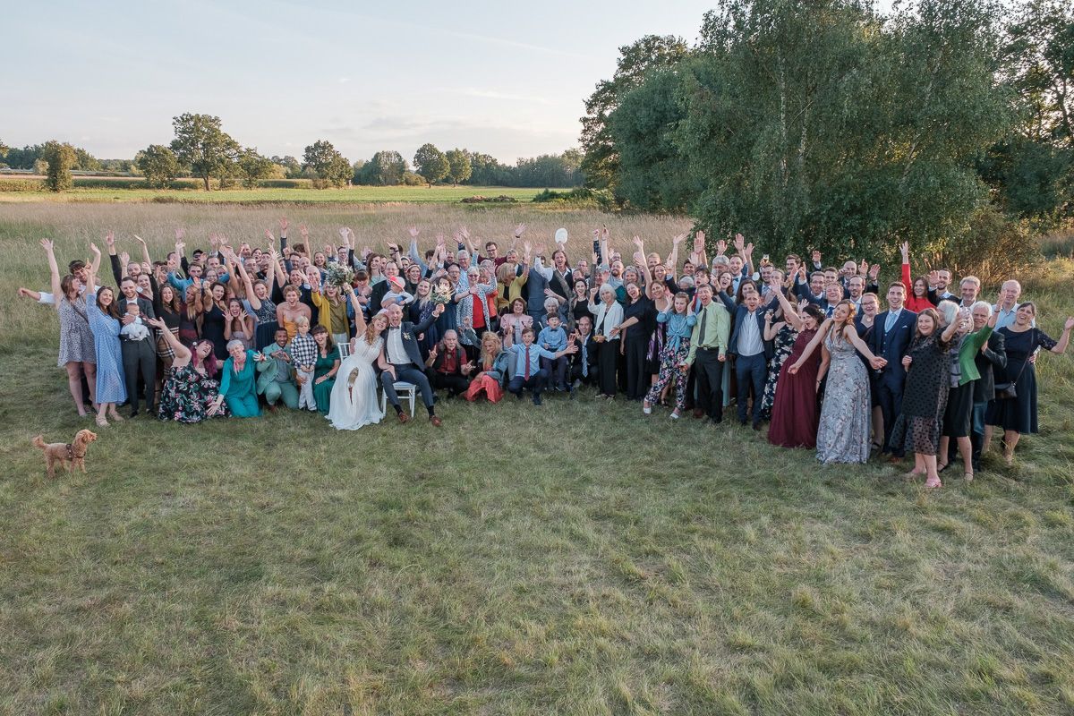 Gruppenfoto aller Gäste auf einer Wiese, alle winken