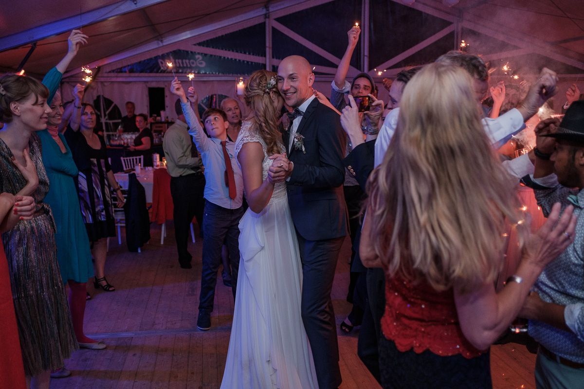 Anna und Jonas tanzen im Festzelt, umringt von Gästen mit Wunderkerzen