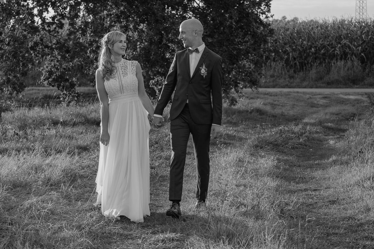 Anna und Jonas gehen Hand in Hand über eine Wiese, in Schwarzweiß